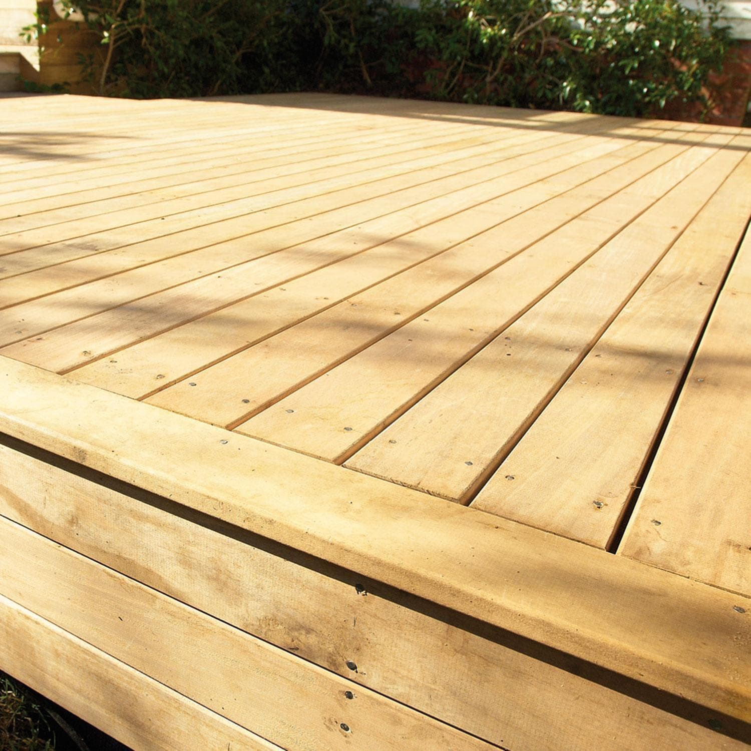Low-set timber deck with a step, bordered by garden planting, in Wellington